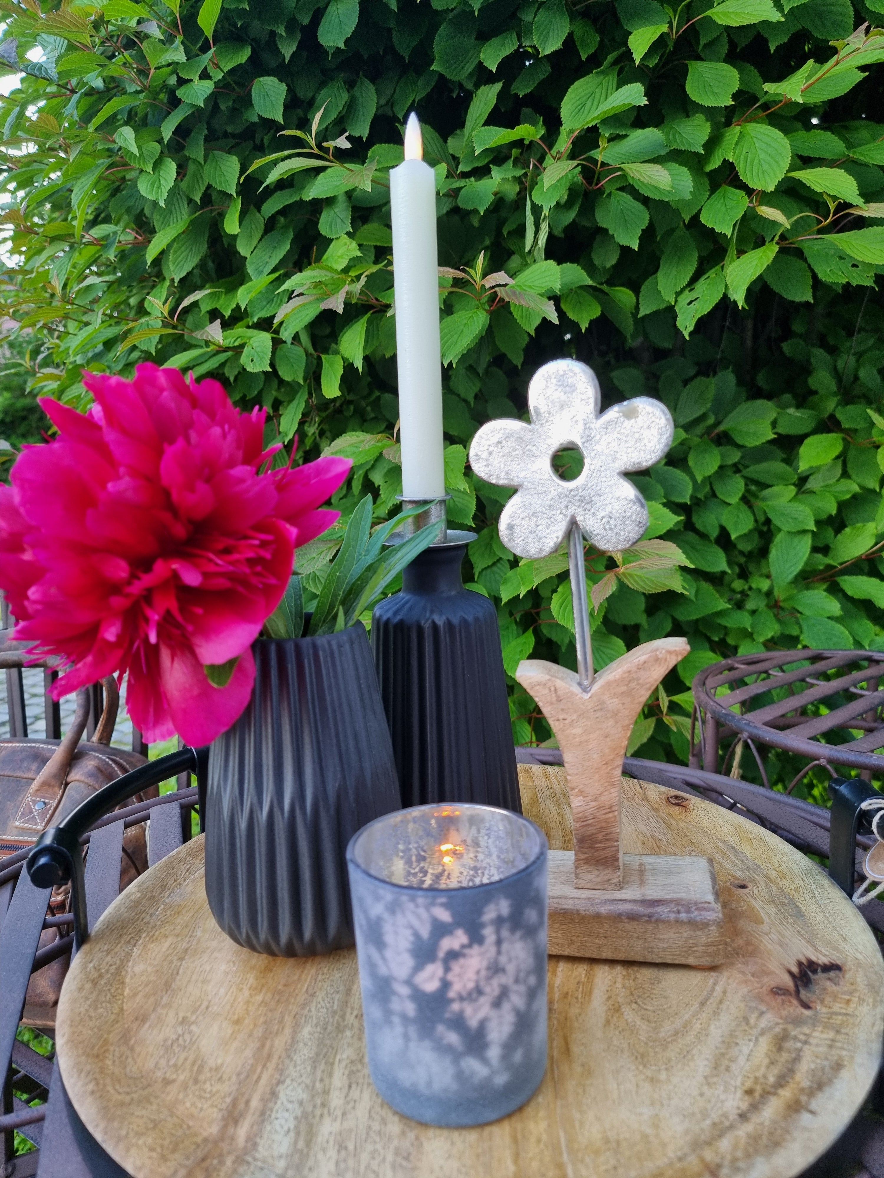 Tablett mit schwarzen Vasen und Windlicht. Draußen auf einem Metalltisch.