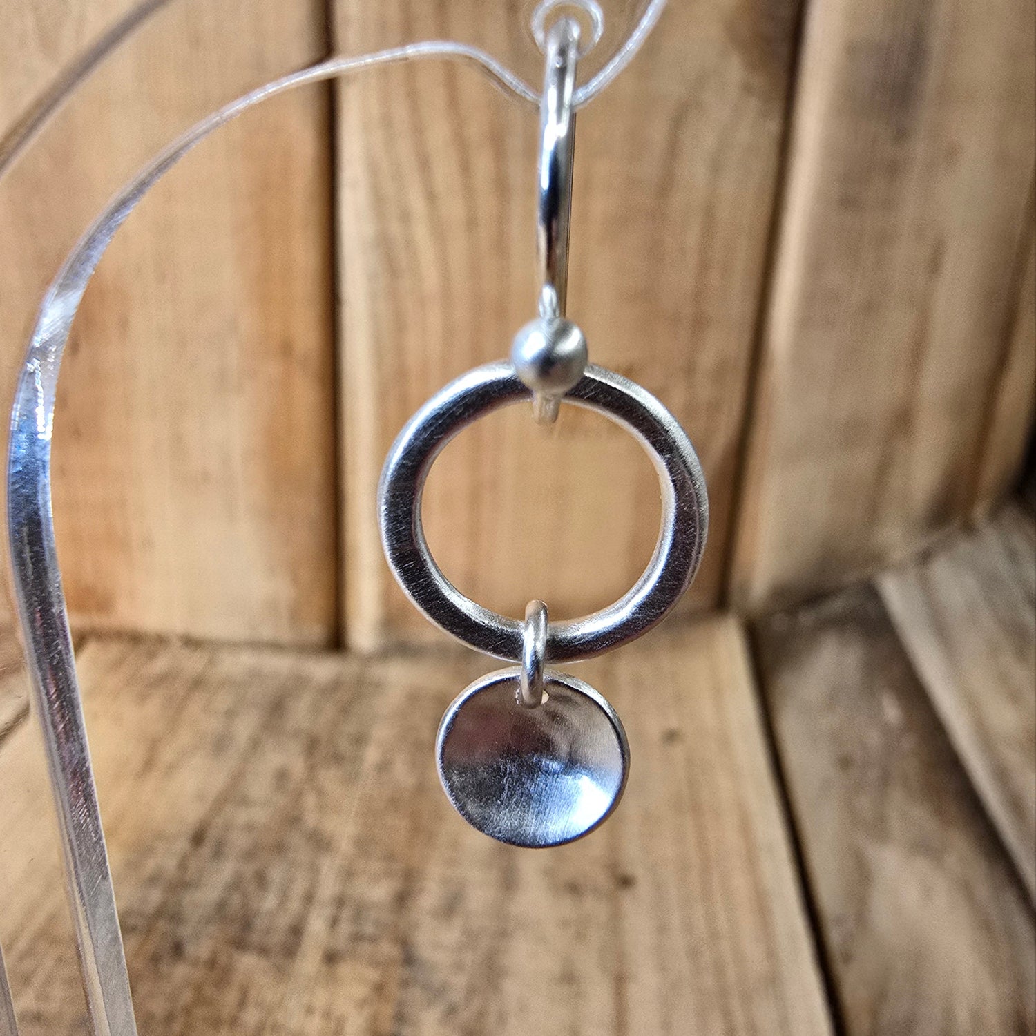 Ohrring in silber matt mit einem Kreis und einem Anhänger