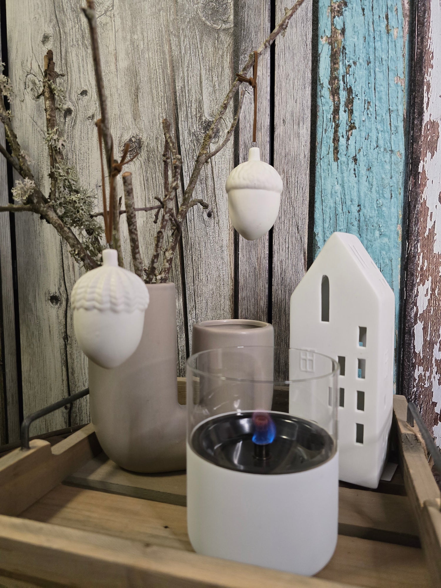 Holztalbett quadratisch mit Vase mit Zweigen und Hängedeko Eicheln sowie  Lichterhaus und Tischkamin