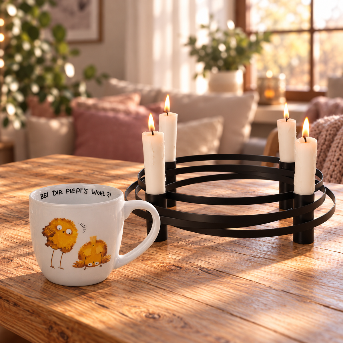 Weiße Tasse mit zwei gezeichneten Küken und dem Spruch “Bei dir piept’s wohl” neben einem schwarzen Kerzenleuchter mit vier brennenden weißen Kerzen auf einem hellen Holztisch im warmen Nachmittagslicht